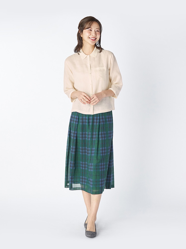 オフホワイトのブラウスとライトグリーンのスカートを着た女性