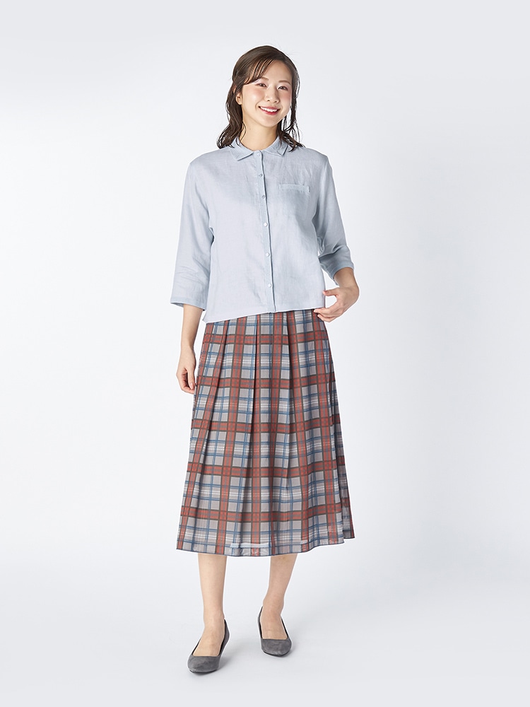 ライトブルーのブラウスとグレーのスカートを着た女性