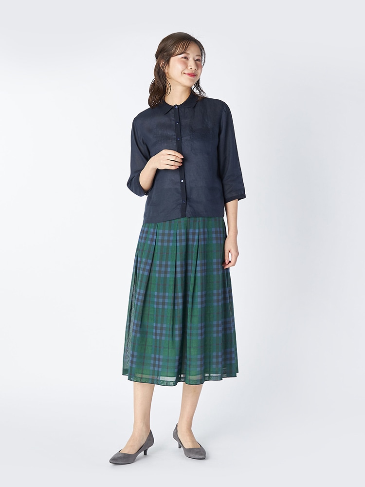 ネイビーのブラウスとライトグリーンのスカートを着た女性