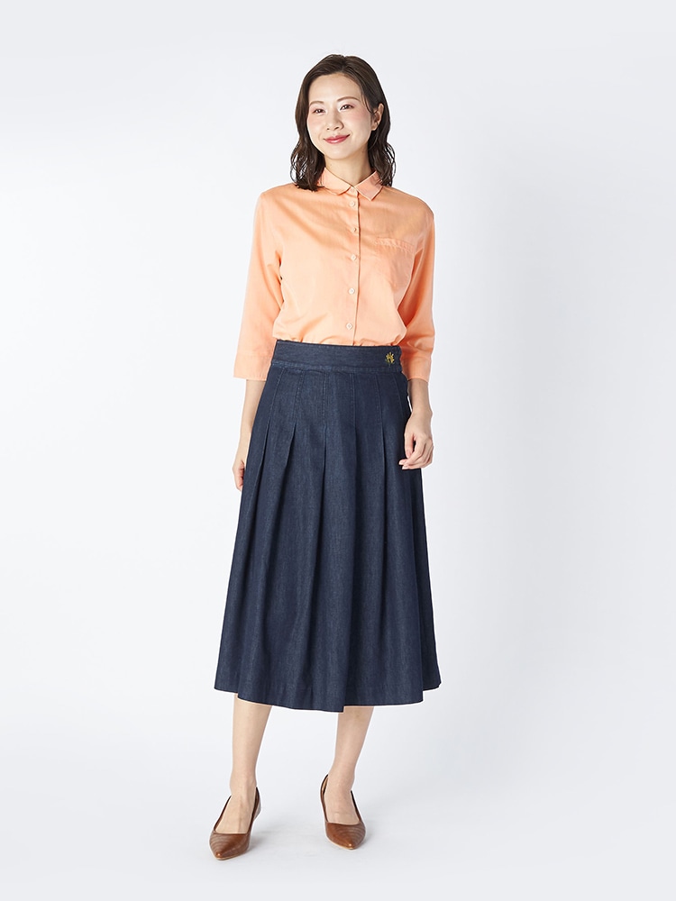 オレンジのブラウスとネイビーのデニムスカートを着た女性