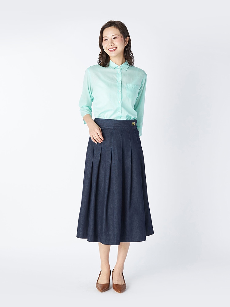 ライトグリーンのブラウスとネイビーのデニムスカートを着た女性