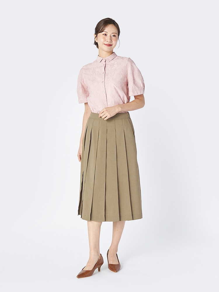 ピンクのブラウスとグリーンのスカートを着た女性