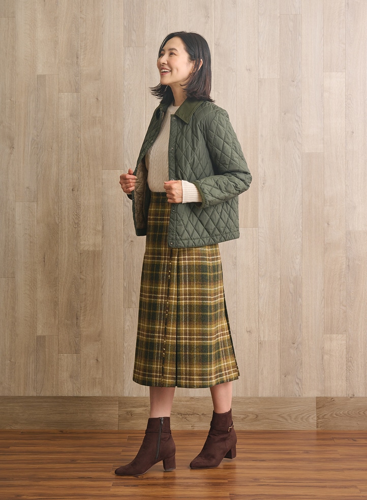 スワローケーブルニットにキルティングジャケットを着用した女性
