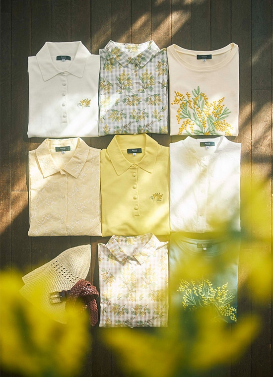 床に並べられたミモザ柄のブラウスとTシャツ、ハットとベルト