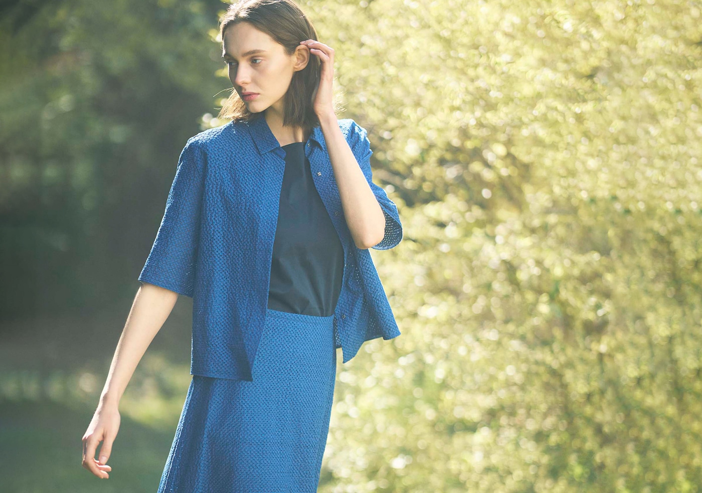 青い半袖ブラウスとスカートを履いた女性