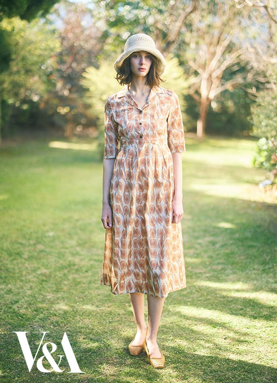 幾何学模様のようなグラデーションのマーブル模様が印象的なロング丈ワンピースを着た女性