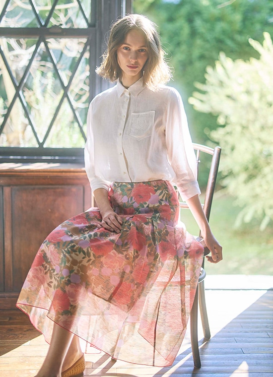 白ブラウスと花柄のシアーピンクのスカートを履いた女性